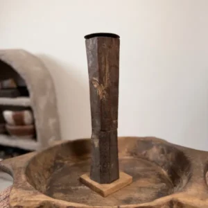 Oude houten baluster kandelaar van donker hout met rechte vorm op een houten schaal in een sober landelijk interieur